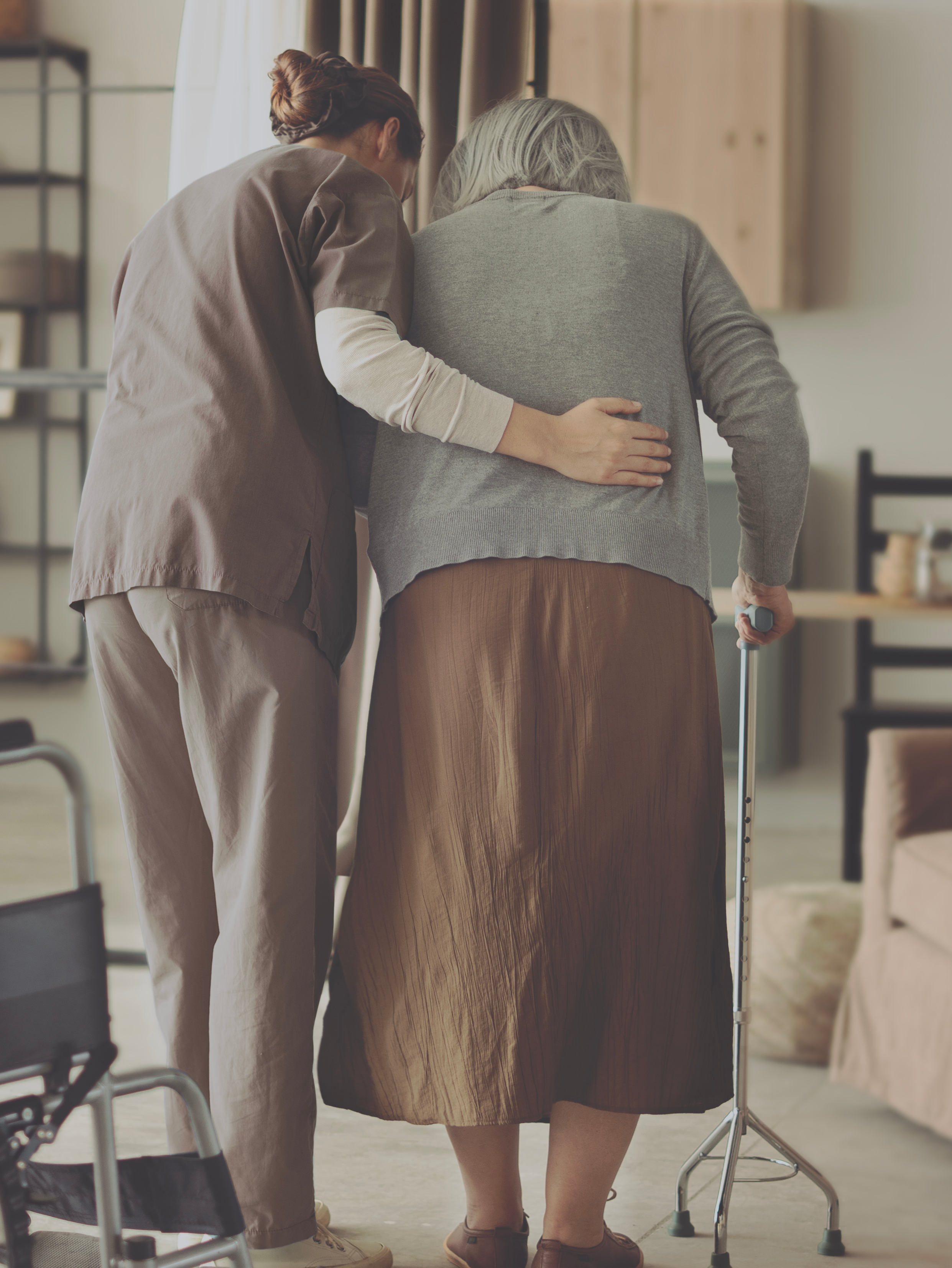 Caregiver assisting elderly woman with walker.