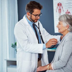 Doctor examining elderly patient with stethoscope.