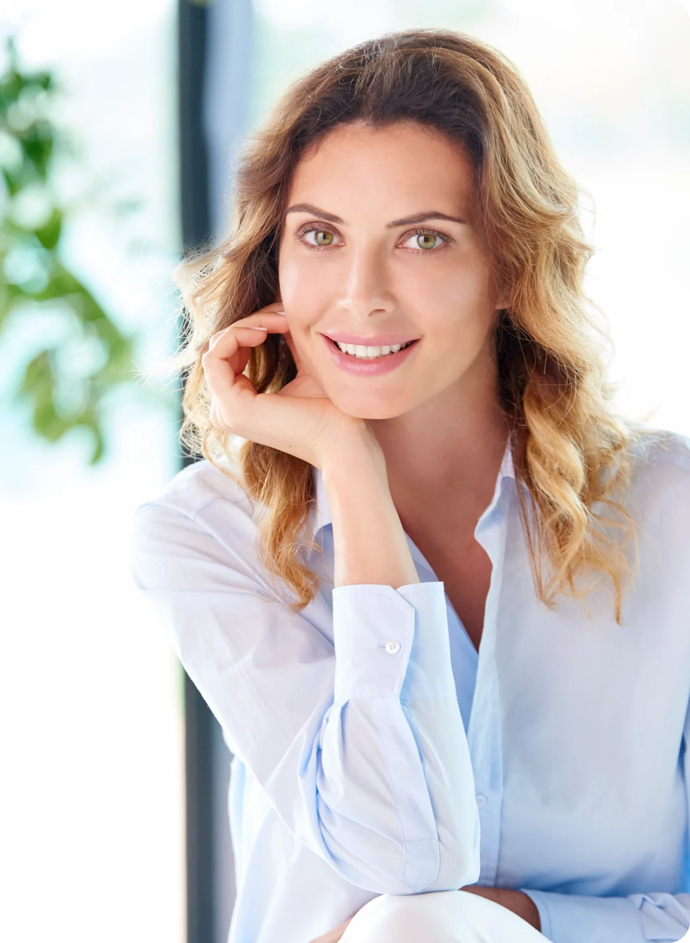 Smiling woman posing in light blue shirt.