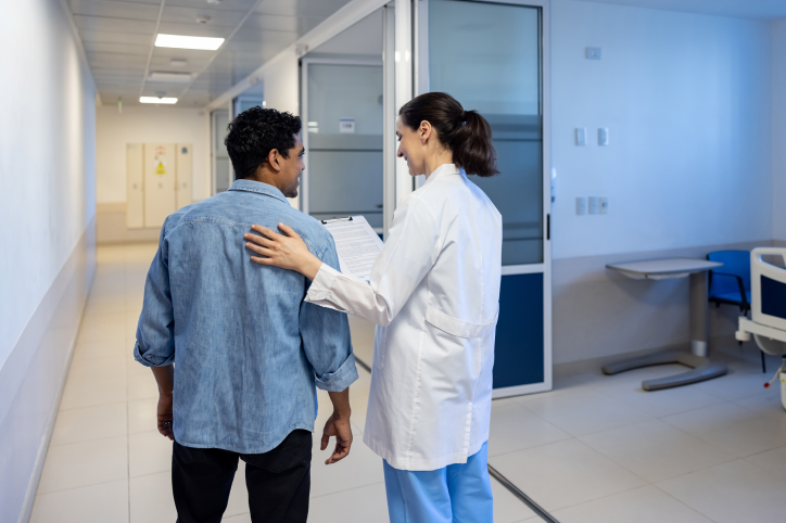 Doctor guiding patient in hospital hallway.